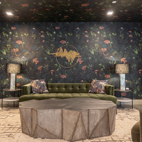 Love where you live Resident lounge with an olive green velvet sofa, arm chairs and side tables, and table lamps against a dark floral wallpaper wall at Enclave at Radius Dilworth in Charlotte, NC.